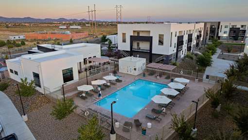 A swimming pool surrounded by lounge chairs and umbrellas is the focal point of the image.