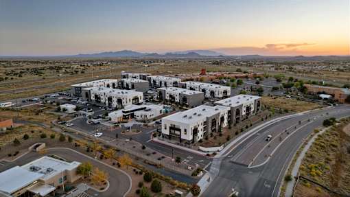 A large white building complex with a parking lot in front of it.
