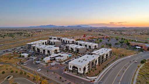 A large white building complex with a parking lot in front of it.