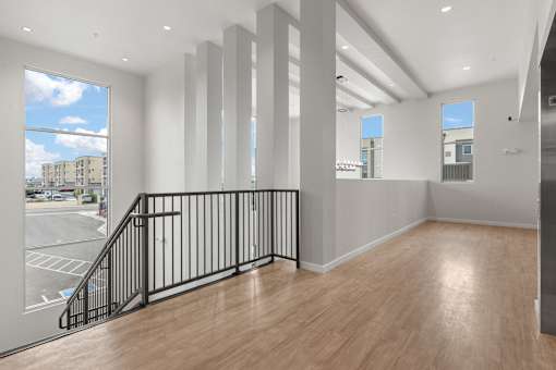 A room with a wooden floor and a balcony with a black railing.