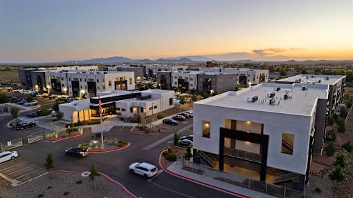 A modern building complex with a parking lot in front.