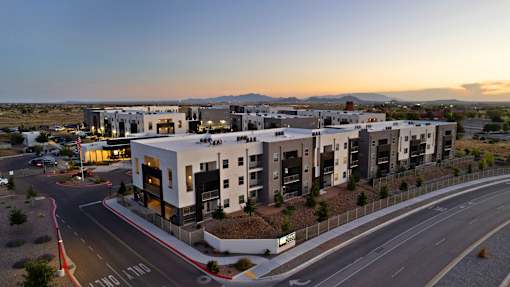 A modern apartment complex is situated on a road with a clear sky above.