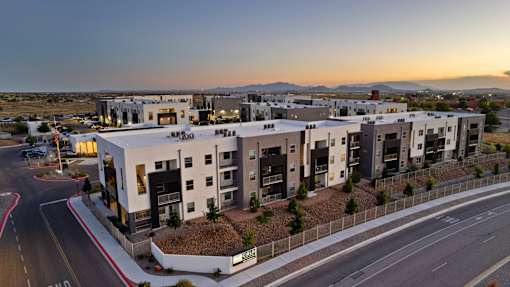 A modern apartment complex is shown with a street in front of it.