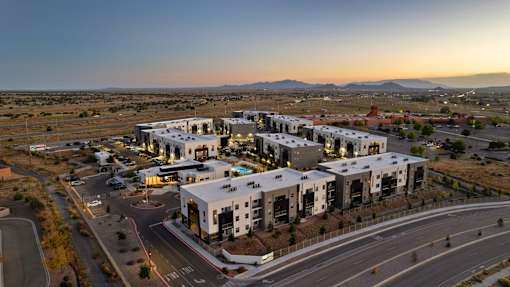 A modern building complex is situated on a road with a clear sky above.