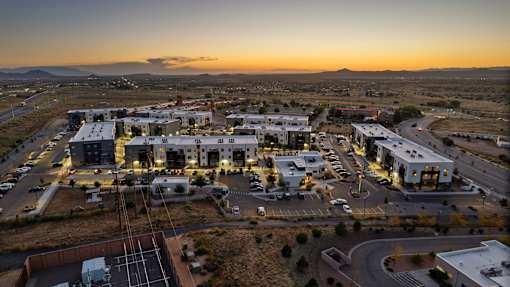 A sunset view of a small town with buildings and a parking lot.