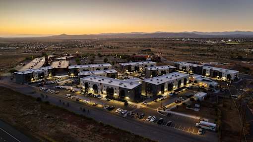 A large industrial complex is lit up at dusk with a mountain range in the background.