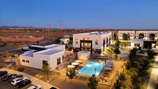 A modern building complex with a pool at night.