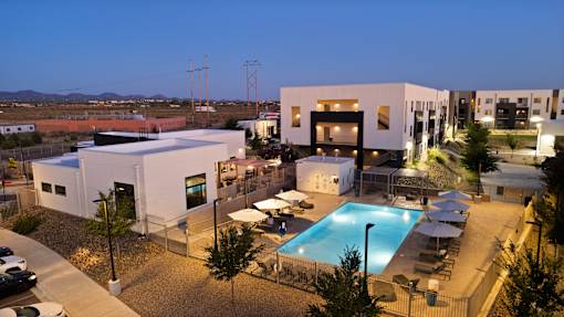 A modern building complex with a swimming pool at night.