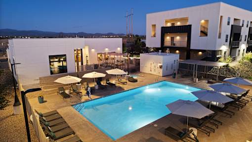 A modern house with a pool and lounge chairs.