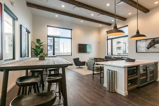 A modern kitchen with a wooden table and bar stools.