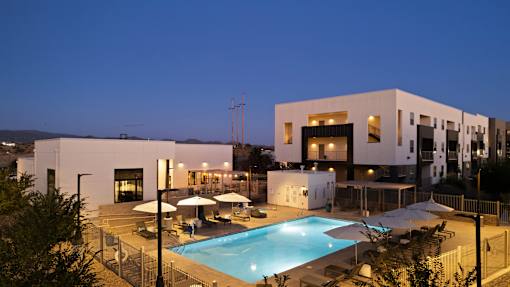 A modern building with a pool in front at night.