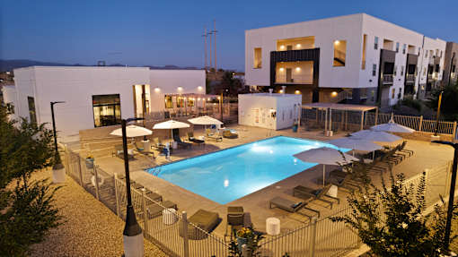 A pool surrounded by chairs and umbrellas at night.