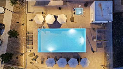 A swimming pool surrounded by chairs and umbrellas.
