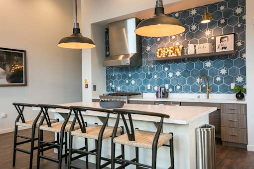 A kitchen with a blue tile backsplash and a large island with four chairs.