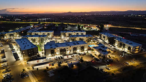 A large resort complex is shown at dusk with lights on and cars parked.