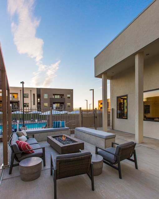 A patio with a fire pit and chairs.