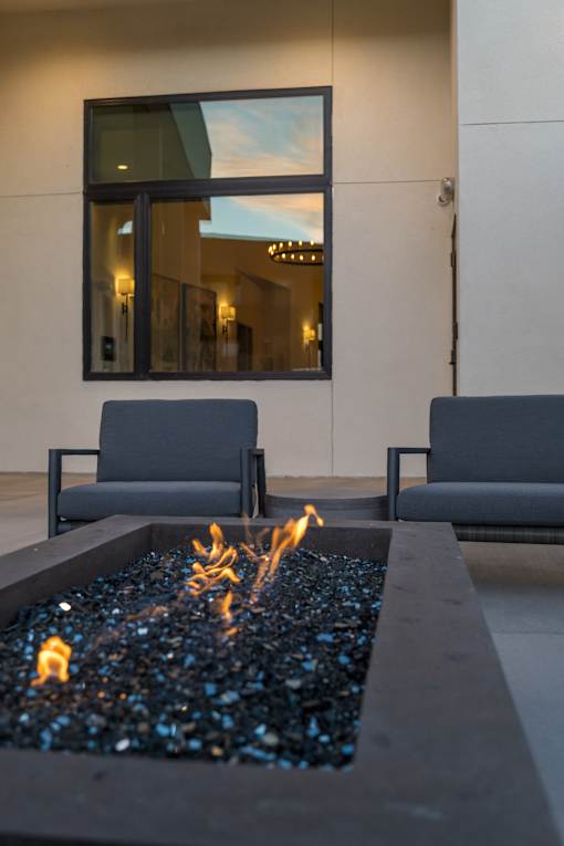 A modern patio with a fire pit and two chairs.