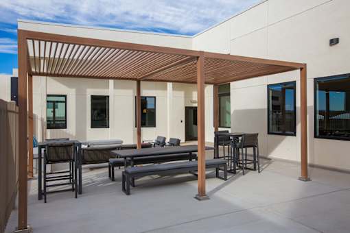 A patio with a table and chairs under a wooden pergola.
