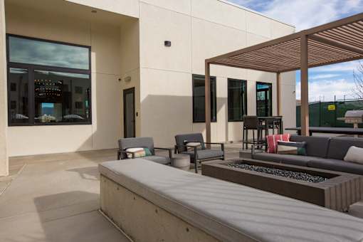 A modern patio with a bench, table, and chairs.