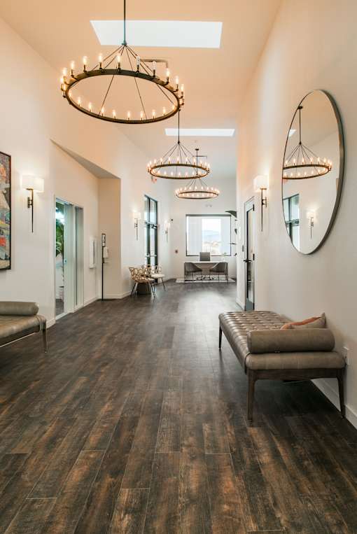A hallway with a bench and a chandelier.