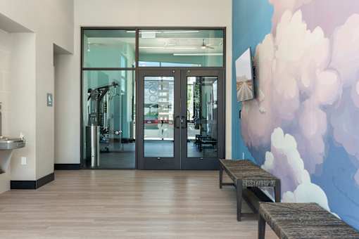 A gym with a row of treadmills and a wall mural.