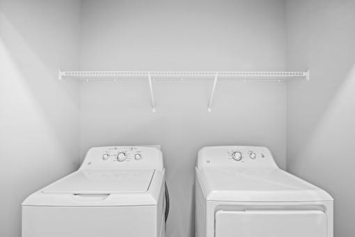 Two white washing machines in a laundry room.