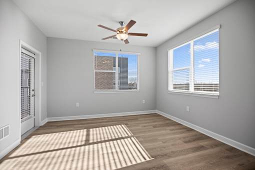 A room with a ceiling fan and a rug on the floor.