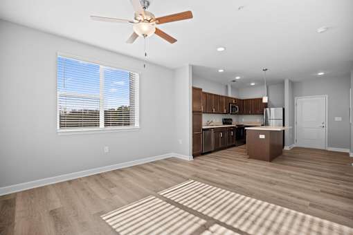 A spacious kitchen and living room with wooden flooring and a ceiling fan.