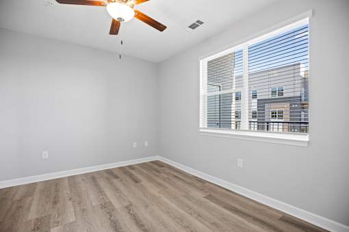 A room with a ceiling fan and a window with blinds.