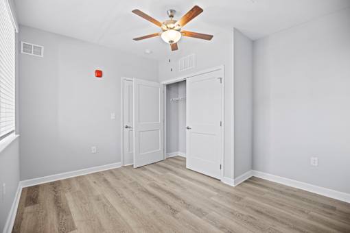 A room with a ceiling fan and wooden flooring.