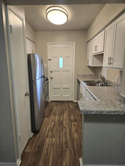 A kitchen with a refrigerator, cabinets, and a countertop.