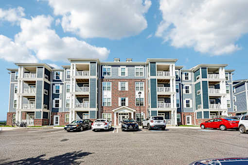 A large apartment complex with cars parked in front.