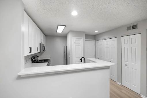 A kitchen with white cabinets and a white countertop.