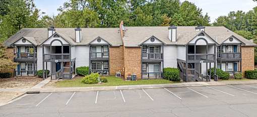 A row of townhouses with a parking lot in front.