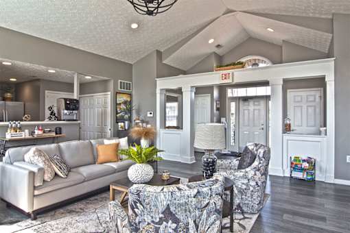 A living room with a grey couch and a grey and white patterned chair.