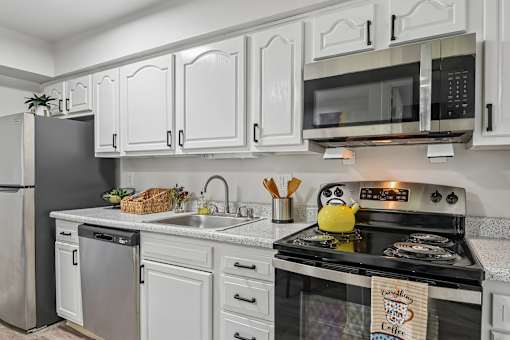 A kitchen with white cabinets and a black stove top.