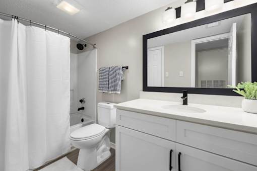 A white bathroom with a toilet, sink, and shower.