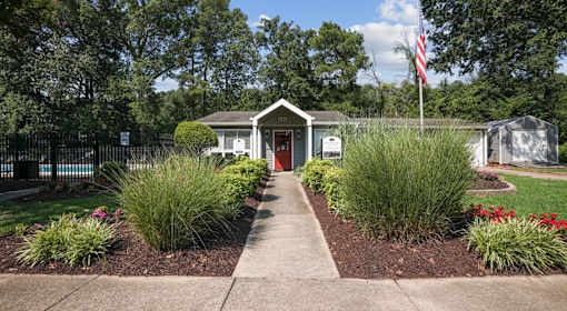 A small building with a red door is surrounded by a garden.