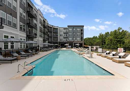 A large swimming pool in front of apartment buildings.