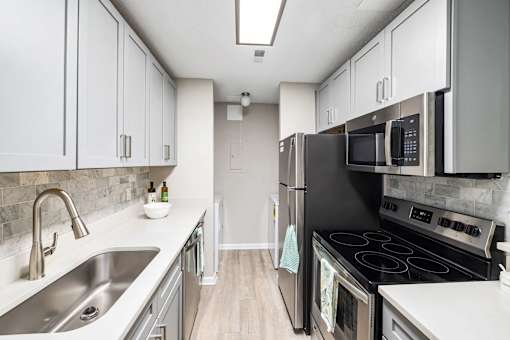A kitchen with black appliances and white cabinets.