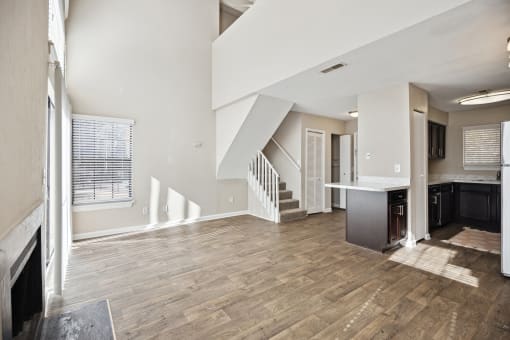 an empty living room with a kitchen and stairs in a house