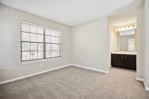 an empty bedroom with a large window and a bathroom
