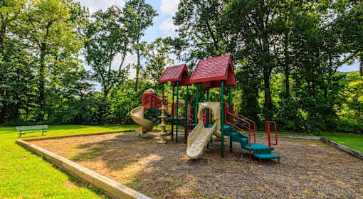 A playground with a red roofed structure and a green slide.