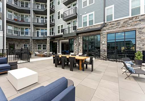 A patio area with a table and chairs is surrounded by apartment buildings.
