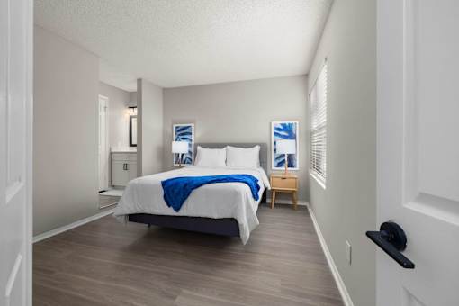 A bedroom with a bed, nightstand, and a window with blinds.