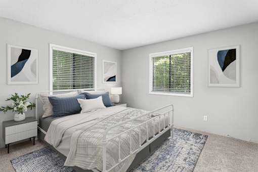 A bedroom with a large bed, a nightstand with a plant, and two framed artworks on the wall.