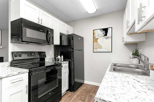 A kitchen with black appliances and white cabinets.