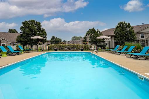 A large blue swimming pool with lounge chairs around it.