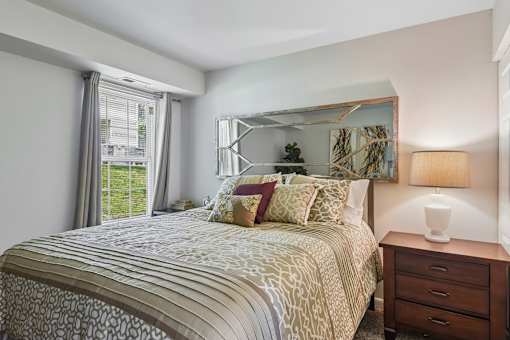 A bedroom with a large bed and a wooden nightstand.