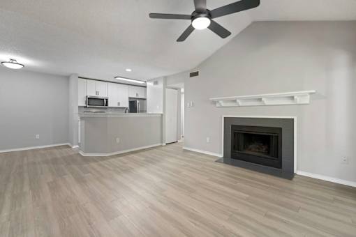 A spacious living room with a fireplace and a ceiling fan.